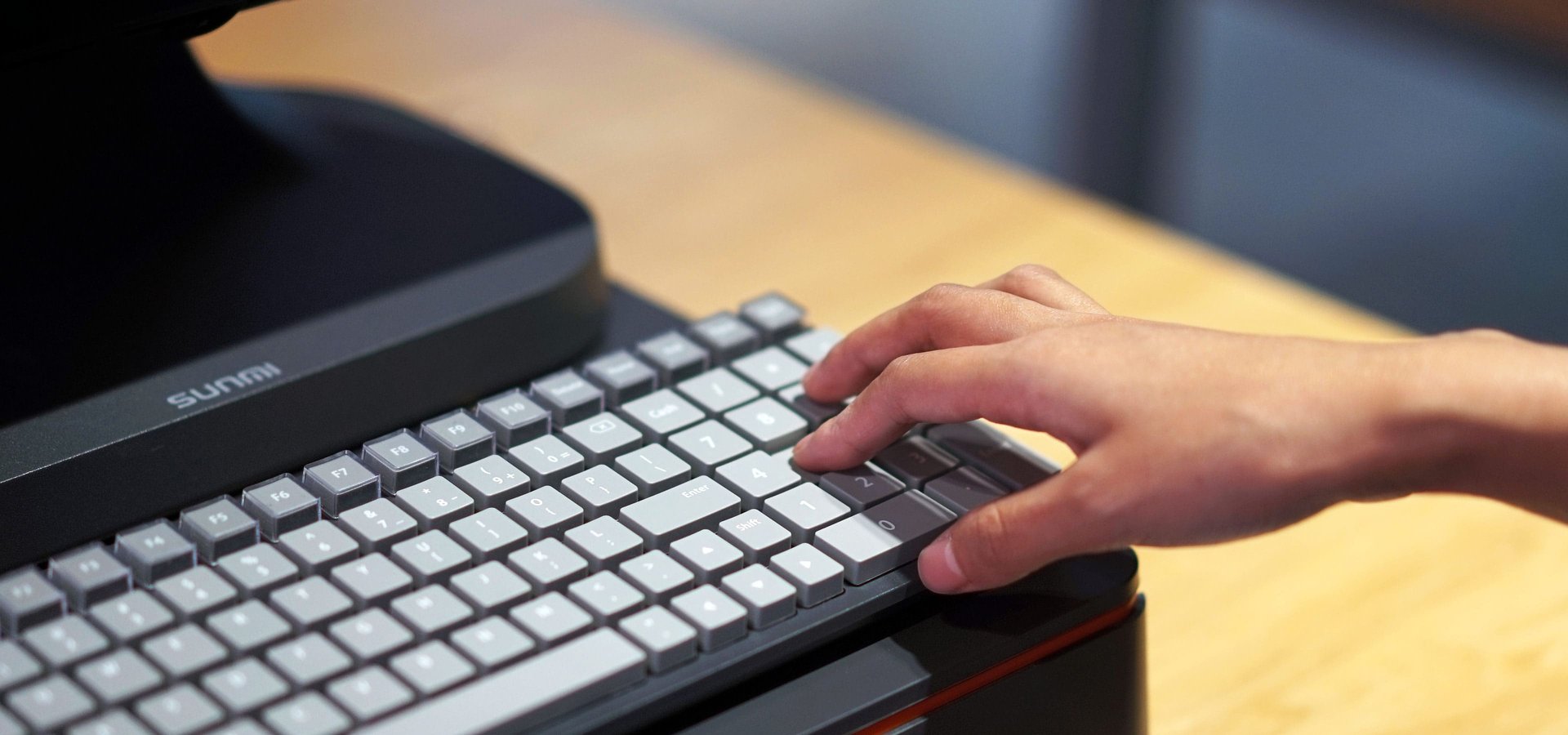 Hand typing on SUNMI keyboard connected to POS terminal